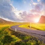View of a road with the sun creeping around the mountains
