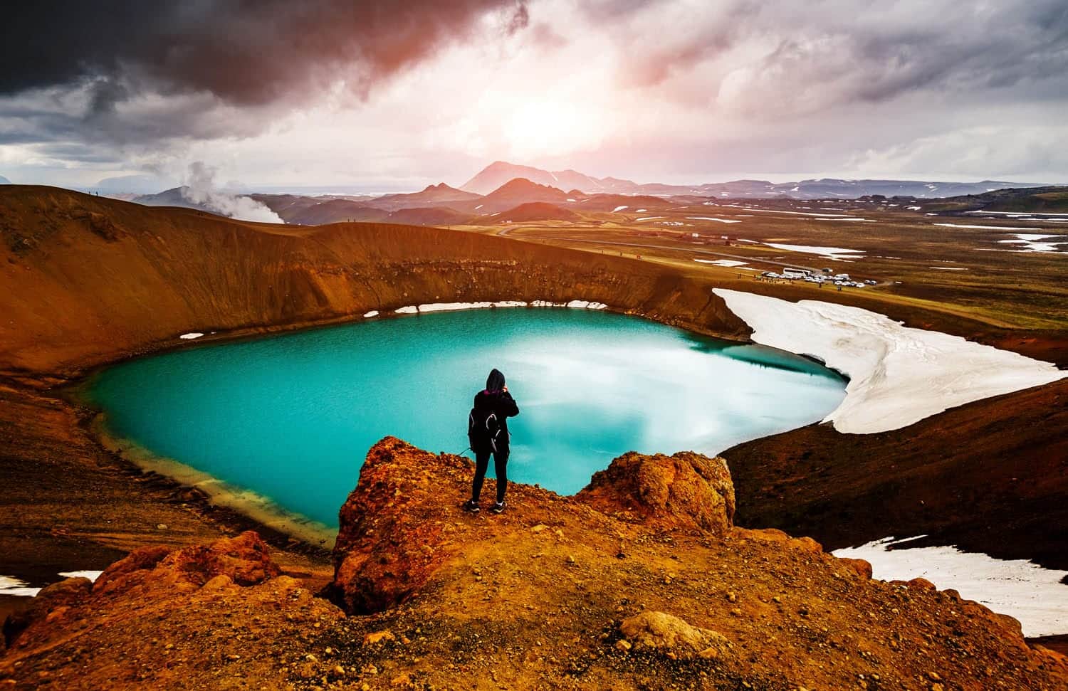 Person standing over Krafla looking into distance, blue water
